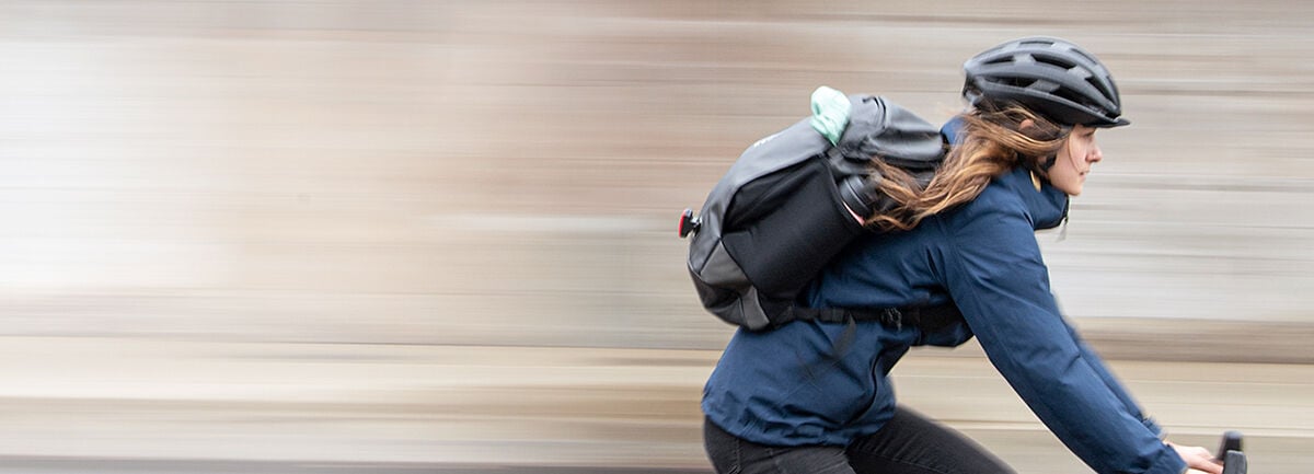 woman riding to work on bike with black backpack and black helmet. 