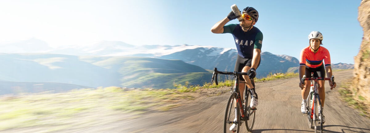 Two cyclists riding down a scenic road.