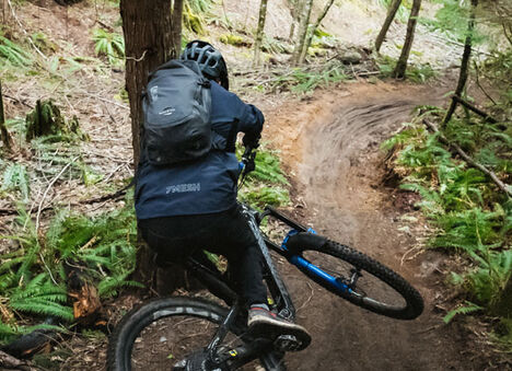 Mountain biker wearing a hydration pack on the trail. 
