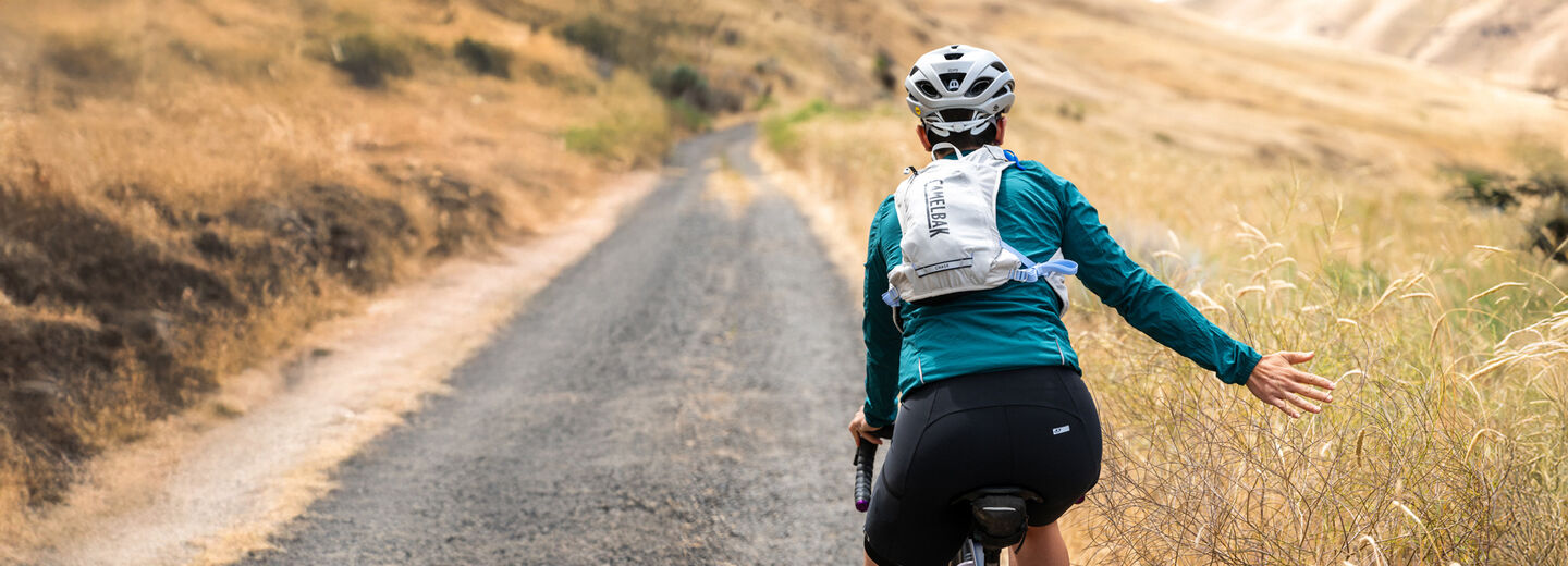 person with a backpack on riding a bike through a field