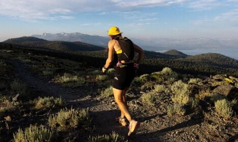 Trail runner at the top of a mountain range with the Apex Pro Run Vest on.