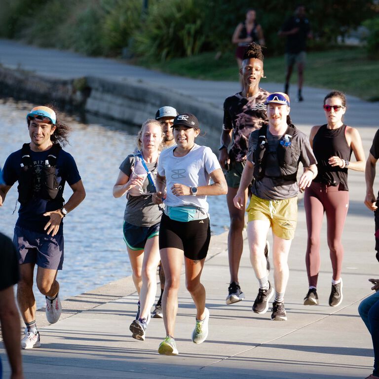 A group of runners jogging by the water.