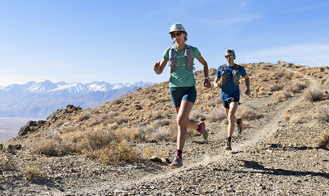 Two runners wearing Rim Runner X Hydration packs running in the mountains
