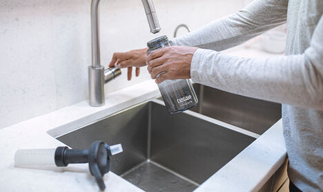 Person filling a bottle with a Lifestraw filter attachment.