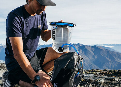 A man taking his Fusion reservoir out of his hiking backpack