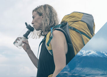 Woman backpacking and drinking out of her bottle.