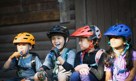 A group of kids with bike helmets and hydration packs on.