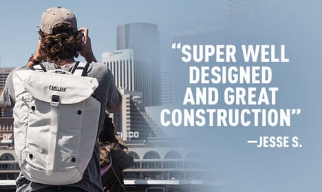 A man wearing an ATP backpack while overlooking San Francisco with a consumer review to the right of him reading, "Super Well Designed and Great Construction" - Jesse S.