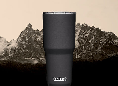 A Black Horizon Tumbler sitting in front of a landscape of snowy mountains in the background.
