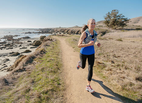 Female runner running on a trail along a waterway. Female runner running on a trail along a waterway.