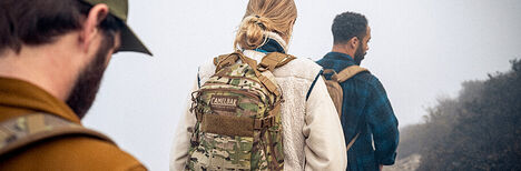 Three hikers going down a foggy trail with CamelBak Milspec Hydration Packs on.