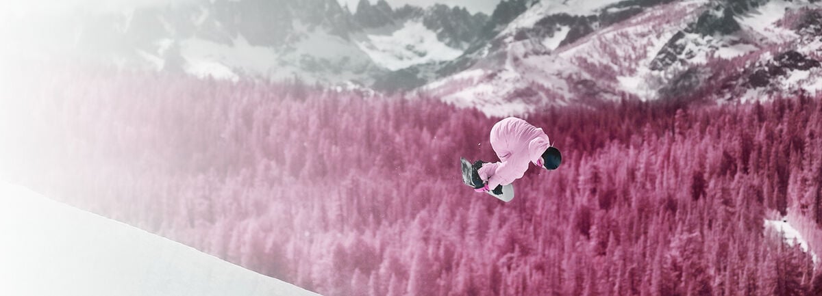 Zoe Kalapos in the air performing a snowboarding trick