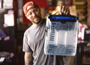 Person holding a CamelBak Group Reservoir filled with water.