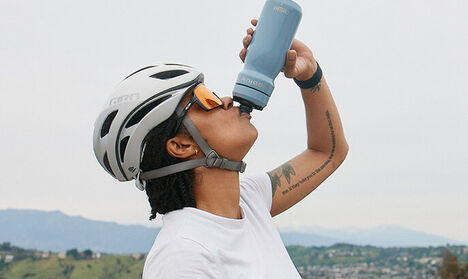 Cyclist drinking from a Podium Steel water bottle.