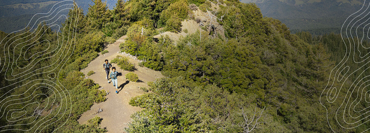 Two hikers on a trail wearing CamelBak Packs
