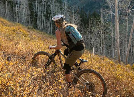 Woman mountain biker on the trail wearing a hydration pack.