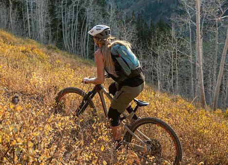 Woman mountain biker on the trail wearing a hydration pack. Woman mountain biker on the trail wearing a hydration pack.