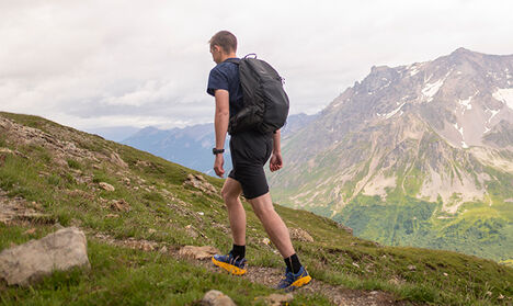 Man walking up a trail with a mountain range in the distance. Man walking up a trail with a mountain range in the distance.