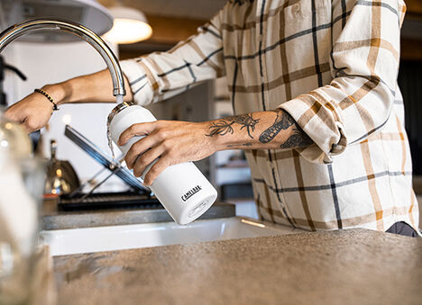 Reusable water bottle being refilled. Reusable water bottle being refilled.