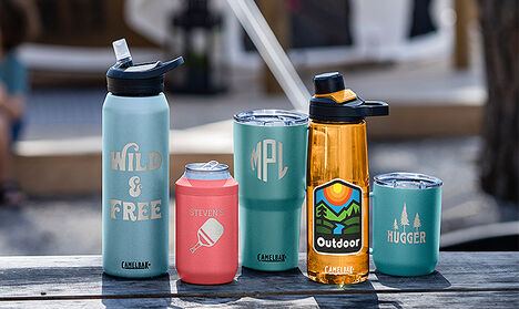 Five custom bottles lined up on a picnic table