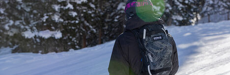 Skier with a POW LE Powderhound hydration pack on in the snow.