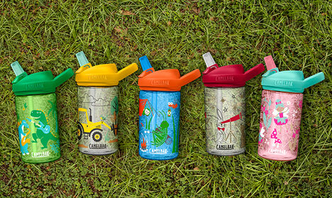 Five limited edition kids Eddy+ 14oz water bottles in a row laying down on grass.