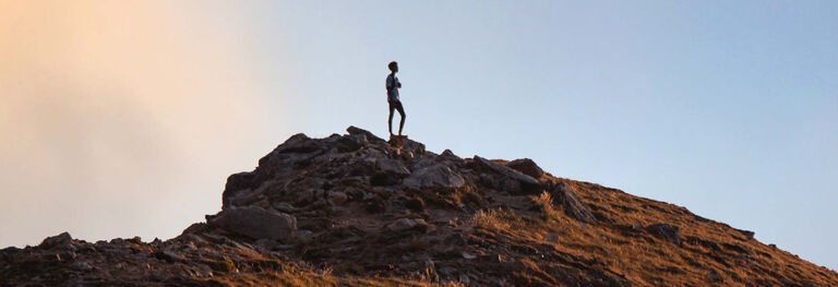 Person standing atop a rocky hill.