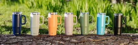 A lineup of multicolored tumblers sitting on a log.