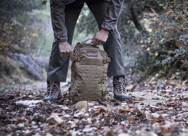 Military pack on a path of gravel and leaves.