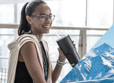 Woman smiling while holding her straw tumbler.