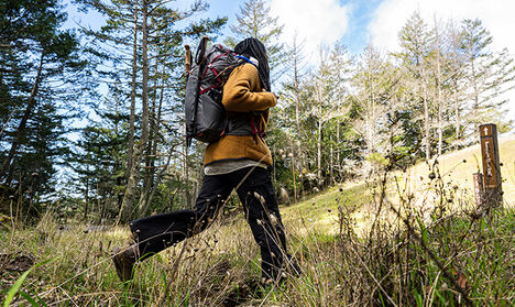 Woman hiking up a trail with her Fourteener hydration pack on.
