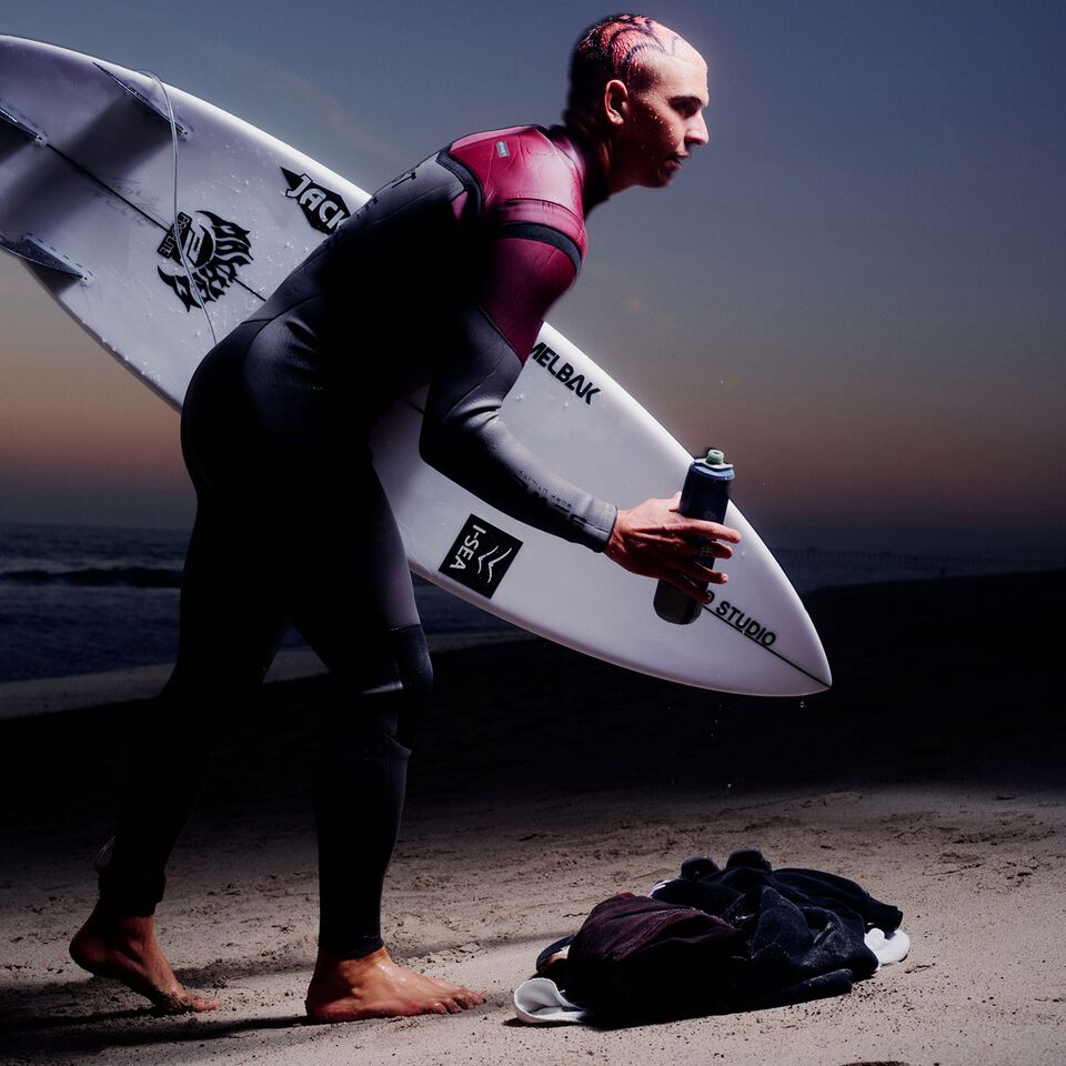 Cole Houshmand holding surfboard and water bottle