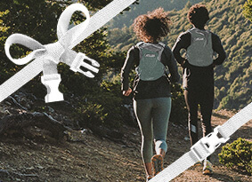 Two runners going down a trail facing away while wearing run vests.