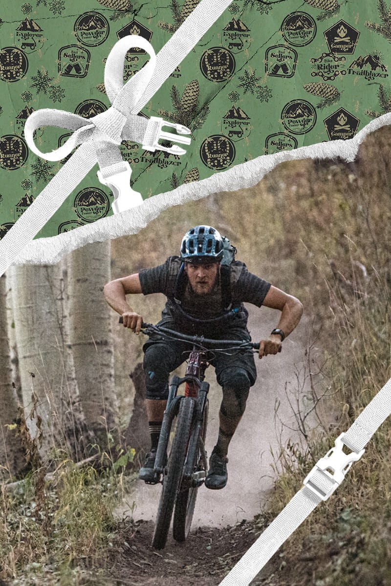 A mountain biker going down a trail with holiday themed wrapping paper framing the area around him. 