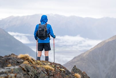 A hiker at the top of a mountain summit, overlooking the valley below.