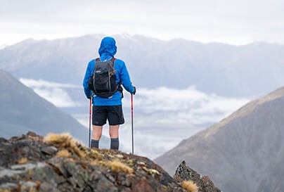 A hiker at the top of a mountain summit, overlooking the valley below.