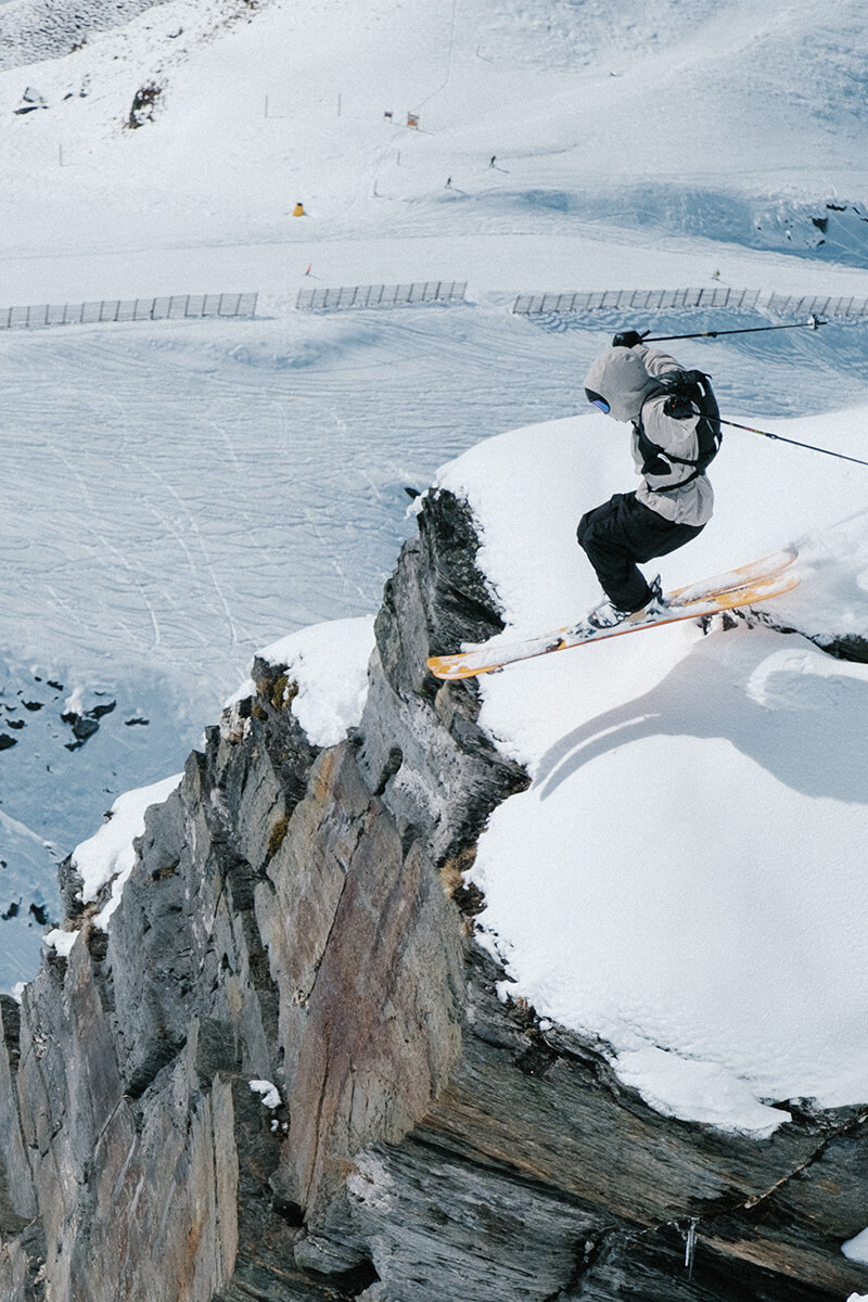 A skier going off a big mountain dropoff