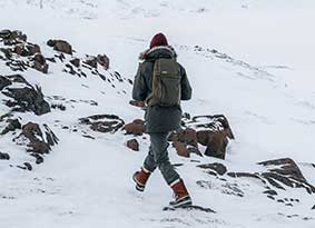 Person walking through snow wearing a hiking pack. 