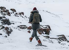 Person walking through snow wearing a hiking pack. Person walking through snow wearing a hiking pack.