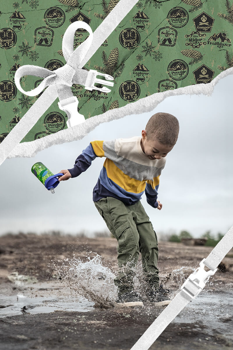 A child playing in a puddle with holiday themed wrapping paper framing the area around him. 