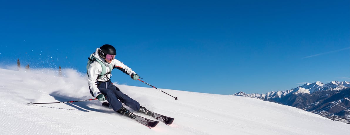 A person skiing down a mountain wearing a CamelBak Snow Pack. 