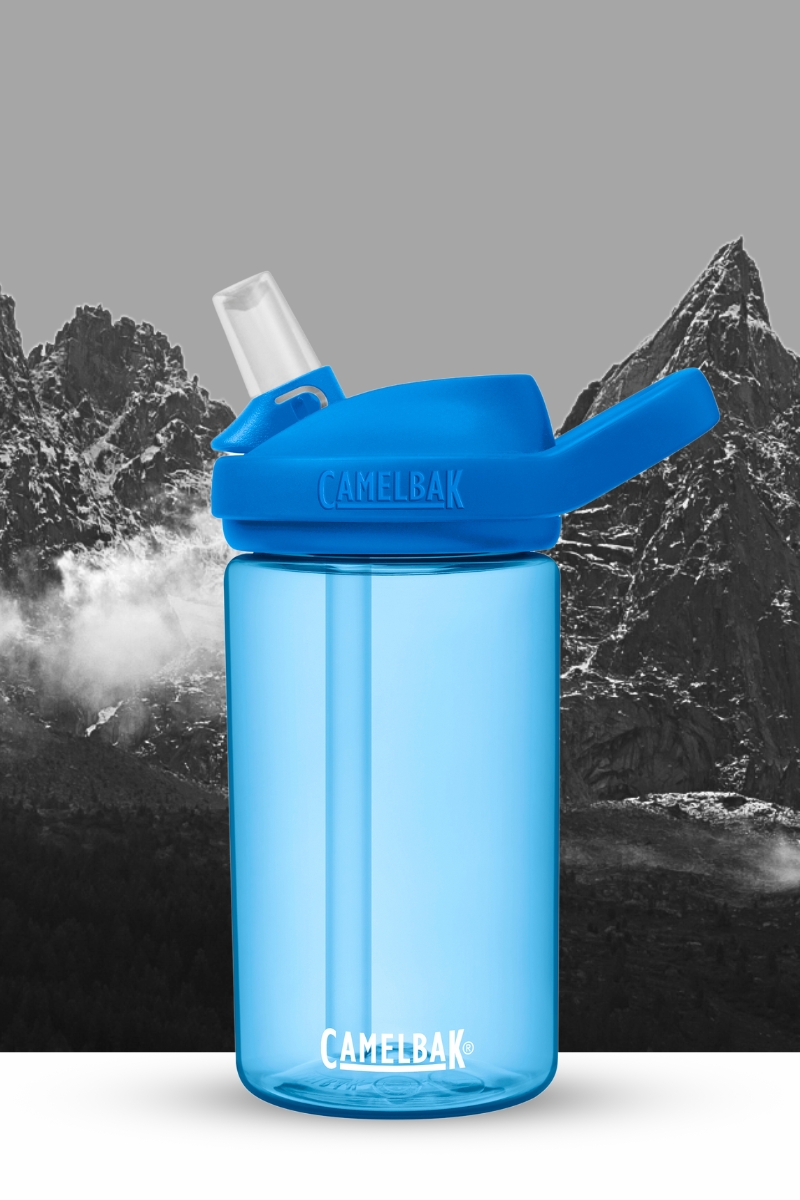A blue kids eddy+ bottle in front of a black and white mountain background.