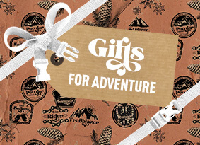Outdoor themed wrapping paper with pack straps as bows and a tag reading "Gifts for Adventure" across the middle.