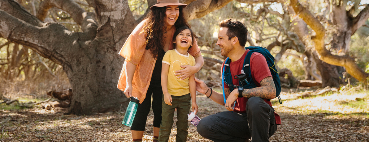 Image of a woman, man and child with water bottles on a trail outdoors. Image of a woman, man and child with water bottles on a trail outdoors.