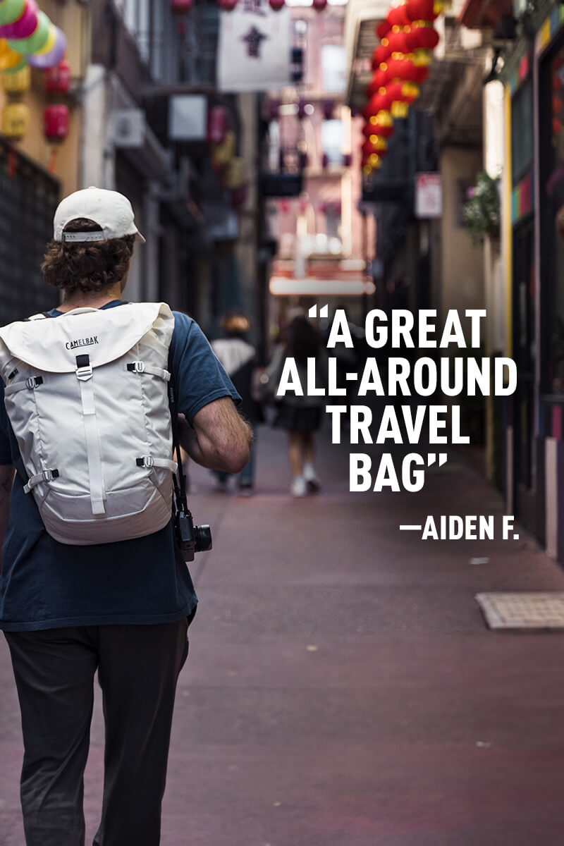 Man walking in downtown San Francisco with an ATP 26 Backpack on. To the right of him is the review of Aiden F., which reads "A Great All-Around Travel Bag"