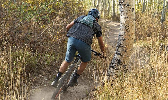 Mountain Biker on trail wearing a hydration pack.